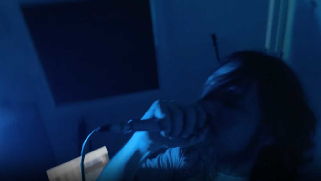 Bo Burnham singing into mic in dark room
