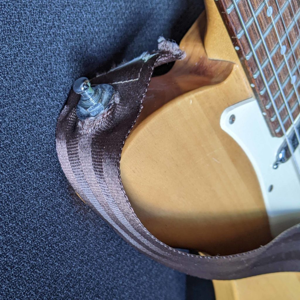 Electric guitar with strap made from a car seat belt.