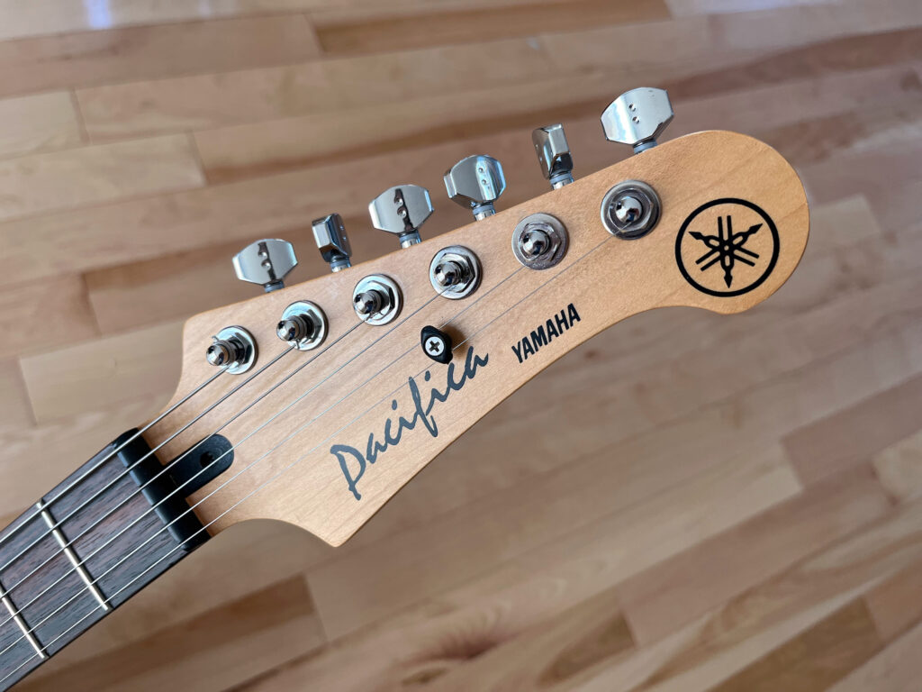 Electric guitar headstock with light wood finish reading "Pacifica YAMAHA" with locking tuners