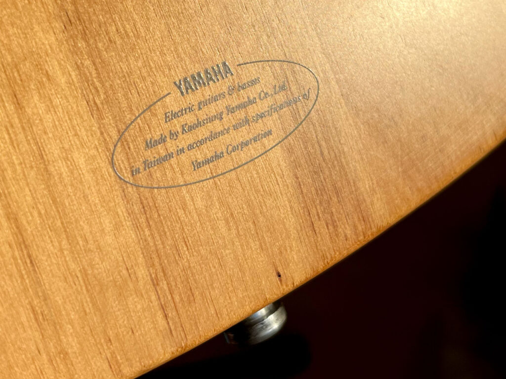 Close-up of back of guitar body with sticker reading: YAMAHA Made by Kaohsiung Yamaha Co., Ltd. in Taiwan in accordance with specifications of Yamaha Corporation