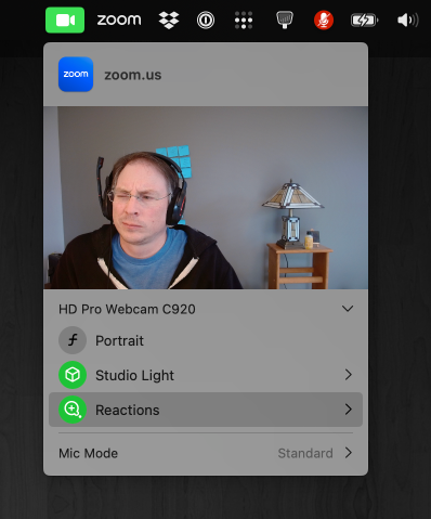 Screenshot of macOS video reactions menu showing a webcam view of a tired dad with a goofy gamer headset on, and user interface elements to control video effects including Portrait, Studio Light, and Reactions.