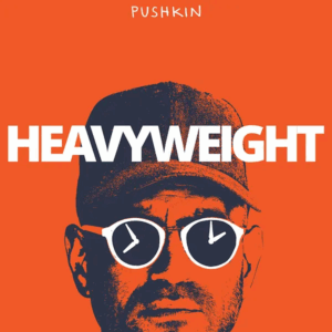 Stylized orange and blue photo of a man with sunglasses with the hands of clocks in each lens, and the title "PUSHKIN HEAVYWEIGHT"